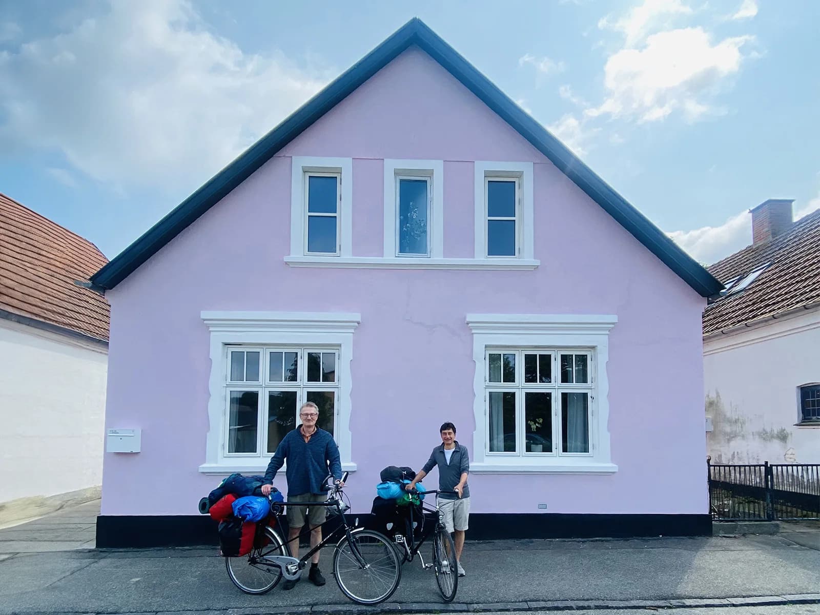 Det lyserøde hus på Elversvej med to cykelturister foran